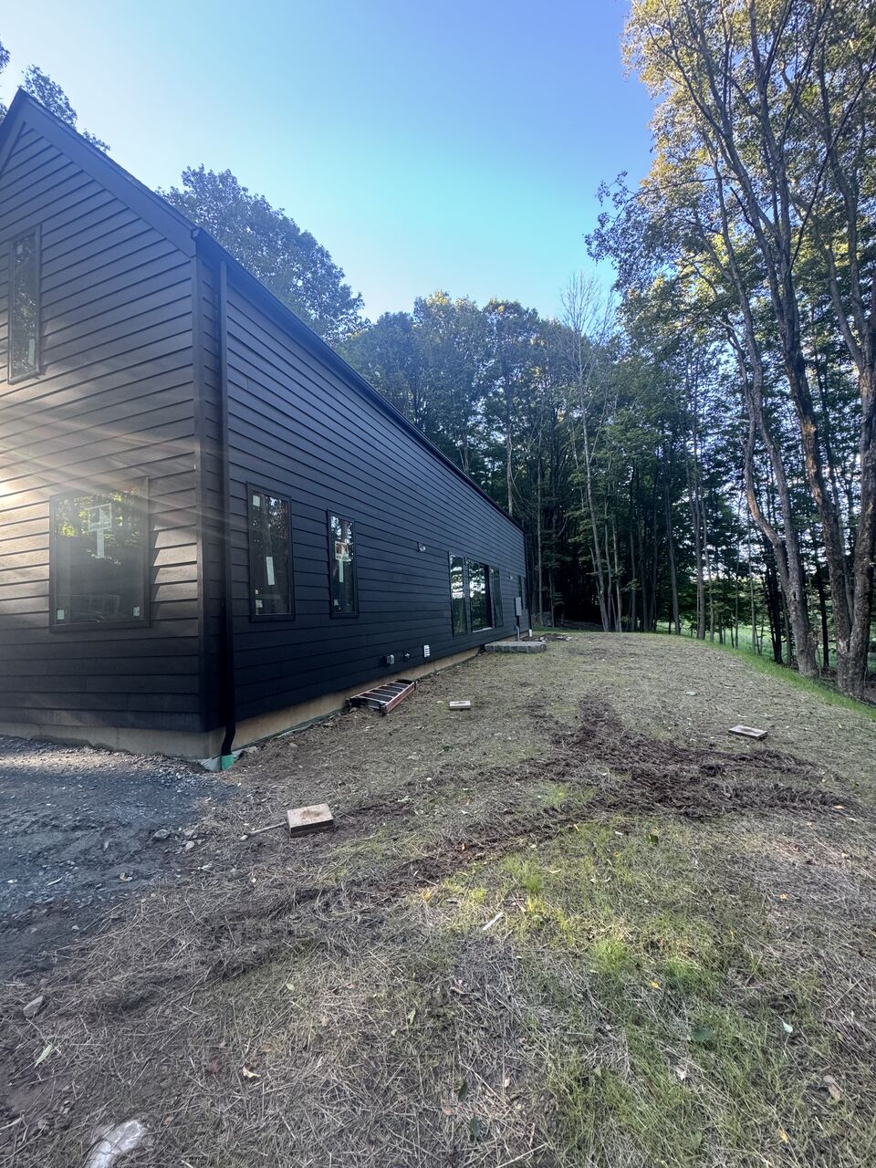 Side elevation of a modern black barn-style house with new gutters