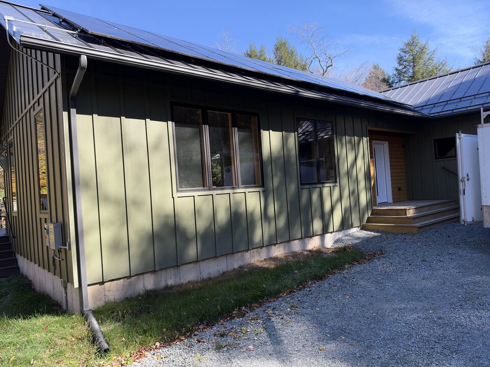New seamless gutter and downspout on a green board-and-batten house